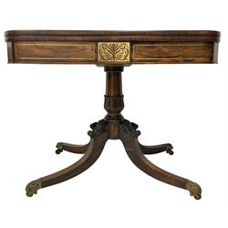 Early Victorian rosewood card table, rectangular swivel and fold-over top with rounded corners, the frieze with inlaid brass stringing and central pierced panel, on foliate carved pedestal with four scroll carved splayed supports, with scroll and shell cast brass castors