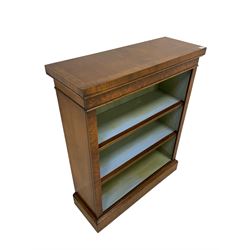 George III design walnut and mahogany open bookcase, rectangular top crossbanded with inlaid stringing, the frieze and uprights figured, the fronts of the two adjustable shelves reeded, om plinth base