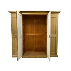 Late 19th century scumbled pine breakfront triple wardrobe or housekeepers cupboard, projecting ovolo cornice, central panelled doors with moulded edges enclosing main cupboard, the left cupboard fitted with upper shelf over hanging rail, the right fitted with four shelves with single drawer to base
