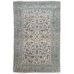 Persian Kashan ivory ground carpet, trailing and interlaced leafy branches interspersed with stylised peony and flowerhead motifs, the border with similar scrolling pattern within guard bands