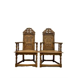 Pair 17th century style oak armchairs, the cresting rail mounted by two lounging figures, panelled back carved with stylised plant motifs and flower heads, moulded seat with four turned pillar arm supports, turned and carved supports joined by plain stretchers 