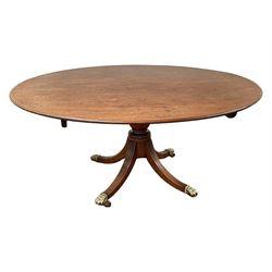George III mahogany breakfast or dining table, moulded oval tilt-top with brass catch, on ring turned vasiform pedestal with four splayed reeded supports, on cast brass hairy paw castors