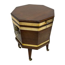 George III mahogany and brass bound octagonal cellarette on stand, hinged lid enclosing fitted interior, with twin brass lion mask mounts and ring handles, the lower moulded edge over square tapering supports with brass cups and castors