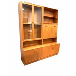 G-Plan - mid century teak display unit, the raised top with two open shelves and illuminated fall front cocktail cupboard flanked by two glazed doors enclosing a further shelf, two double cupboards under, raised on plinth base W163cm, H200cm, D46cm