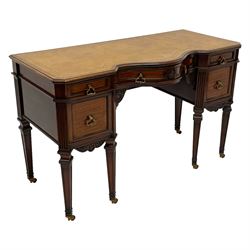 Late 19th century mahogany writing desk, rectangular moulded top with serpentine break-front, tooled leather inset, fitted with three drawers and two cupboards, the central drawer with flower head carving, scrolled acanthus leaf brackets, canted upright corners with fluted decoration, on square tapering supports with recessed panels and spade feet, brass cups and castors 
