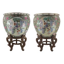 Pair of 20th century Chinese Famille Rose fish bowls, each painted to the exterior with panels of figures in a courtyard setting, against a dense millefleur and gilt ground, on hardwood stands, D48cm x H40cm (bowls)