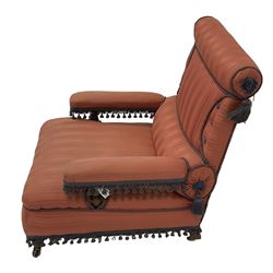 Late 19th century Howard design armchair, upholstered in coral pink striped fabric with indigo fringing, the cresting rail and lumber support with bolster design, raised on turned supports with castors