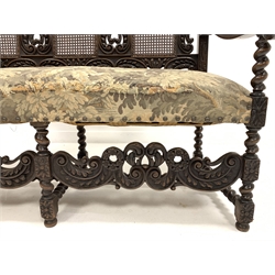 Early 20th century William and Mary style walnut hall seat, with cane panels to back, profusely carved with floral scrolls and foliate, upholstered seat, raised on spiral turned supports and stretchers