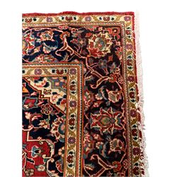 Small Persian Kashan crimson ground rug, indigo ground and floral decorated central medallion and spandrels, the field decorated with trailing branches and stylised plant motifs, repeating floral design border