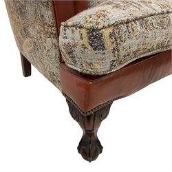 Traditionally shaped wingback club armchair, upholstered in part paisley patterned fabric part tan leather with leather piping, hardwood framed, on ball and claw carved feet, together with complementary scatter cushion 