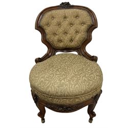 Victorian walnut framed nursing chair, floral carved cresting rail, shaped back and sprung circular seat upholstered in foliate patterned sage green fabric, flower head apron over cabriole feet