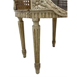 Late 20th century French style three-tier stand or lamp table in painted finish, the oval top with white, pale orange and black veined marble top, the rim carved with repeating geometric design, oval apertures carved with laurel leaf garlands, fitted with two marble shelves, cane work sides with applied foliate garlands, turned and fluted supports