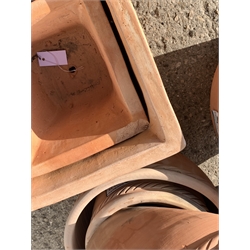Twenty circular terracotta plant pots with rope twist rims and four square tapering terracotta plant pots, various sizes