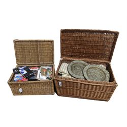 Two wicker baskets, containing VHS tapes, fabrics and two round brass plaques
