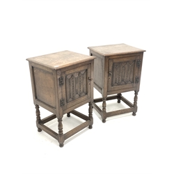 Pair of early 20th century oak bedside cupboards, with fielded panelled doors carved with linen folds, raised on turned supports united by stretchers