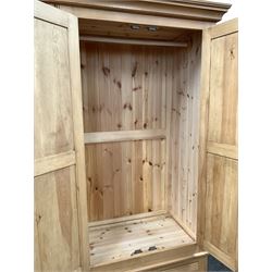 Solid pine four door wardrobe enclosing interior fitted for hanging, with three base drawers, raised on bun supports 