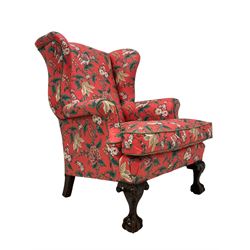 Late 19th to early 20th century wingback armchair, upholstered in 'Givenchy for Fabriyaz' fabric, pink ground and decorated with trailing floral pattern, upholstered seat cushion and sprung seat, on foliage carved ball and claw feet 
