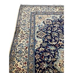 Persian nain ivory ground rug, silk inlaid, the central lotus medallion in an indigo field decorated with scrolling foliate patterns and flower heads with matching spandrels, the guarded border with trailing stylised floral motifs