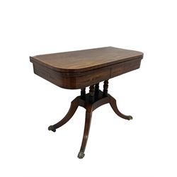 Regency mahogany crossbanded foldover table, with ebony strung frieze, on turned supports, quadripartite base and four sabre legs with brass paw feet and castors