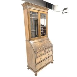 Early 20th century oak bureau bookcase, lunette carved frieze over two tracery glazed doors enclosing three shelves, fall front under revealing fitted interior, two short and two long drawers to base, turned supports 
