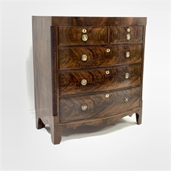Early 19th century figured mahogany bow front Trafalgar chest of three long and two short drawers, with satinwood stringing to edge and apron, rope twist decoration to side pilasters and escutcheons, circular brass plate ring handles, shaped apron, raised on bracket supports, W101cm, H110cm, D52cm