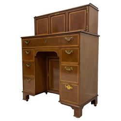 Edwardian mahogany kneehole secretaire desk, with satinwood crossbanding bordered with ebony and boxwood stringing, the rectangular top with cavetto gallery, rectangular detachable structure with central fall front door enclosing two satinwood fronted l drawers, flanked by panel doors enclosing pigeonholes, the projecting base with long fall front frieze drawer with inset writing surface, above six graduating drawers with central cupboard, raised on square feet with casters, stamped Collmann & Scantlebury