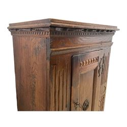 18th century carved oak standing cupboard, moulded projecting cornice over carved dentil decoration, the single panelled door with moulded slip decorated with **, the uprights carved with vertical arcade decoration and foliate design, with wrought metal fittings and handle, raised on bun feet