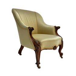 Victorian rosewood armchair, scroll carved arm terminals, the shaped uprights carved with foliage, upholstered in pale yellow fabric, on scroll carved cabriole supports with brass and ceramic castors, sprung seat
