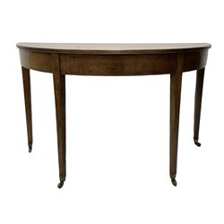 George III mahogany demi lune side table, raised on square tapering supports, terminating in brass castors 