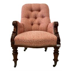 19th century mahogany armchair, upholstered in buttoned pink foliate patterned fabric, scrolled arm terminals with carved decoration, raised on turned supports with castors