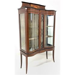 Edwardian mahogany serpentine display cabinet, the raised back inlaid with boxwood stringing, cornucopias issuing flowers centred by fan, over frieze with further inlay, two doors enclosing two shelves, raised on slender square tapered and splayed support W107cm, H178cm, D40cm