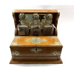 Victorian oak tantalus with silver-plated mounts, holding three square-cut glass decanters, two with silver collars and the other with a Charles Rennie Mackintosh pewter label, with two hinged doors enclosing two compartments and secret drawer beneath, L38cm x H34cm 