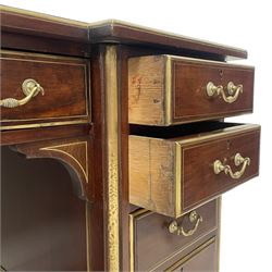 Edwardian walnut twin pedestal writing desk, moulded reverse break-front top with raised gallery and leather inset, fitted with nine drawers, brass stringing and edge mouldings throughout the top and drawer fronts, on tapering feet with brass castors 
