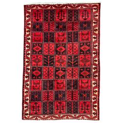 Persian Lori Bakhtiari crimson ground rug, the field decorated with a chequerboard layout of dark indigo and red panels containing stylised plant and geometric motifs