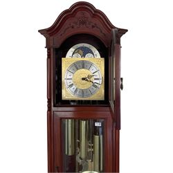 An impressive 20th century longcase clock in a mahogany case with an arched pediment, glazed and fretted side panels and glazed case door, break-arch hood door with a conforming brass dial displaying a working moon phase disc and silvered chapter ring with Roman numerals and minute track, with decorative steel hands, gridiron pendulum and triple train West German weight driven movement chiming on the quarters and striking on the hour, with a selection of Westminster, St Michael, and Whittington ¼ chimes on 12 gong rods. With three brass cased weights.

