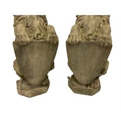 Pair cast stone seat lions, each holding shield, on canted rectangular plinths