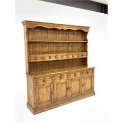 Pine four drawer kitchen dresser, two height plate rack with five spice drawers, four drawers and four panelled cupboards under enclosing shelf, skirted base, W183cm, H200cm, D42cm