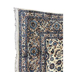 Persian ivory ground rug, the field decorated with scrolling foliate branches and palmette motifs, surrounded by a guarded border with indigo detailing and repeating interlacing stylised plant motifs