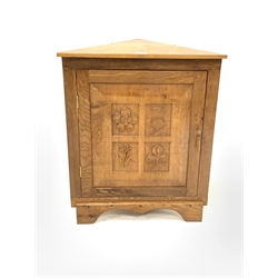 Yorkshire oak floor standing corner cupboard, with sngle fielded panelled door carved with floral decoration, enclosing one shelf, raised on shaped plinth base 