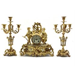 Late 19th century alabaster and gilt figural mantel clock garniture, white enamel dial with Arabic chapter ring, striking hammer on bell, and a pair of four branch candle sticks 