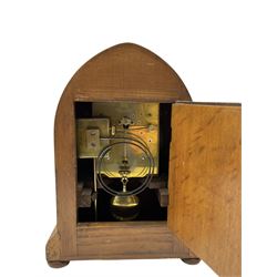 German - early 20th century 8-day oak cased striking mantle clock, striking the hours and half hours on a coiled gong, in a lancet shaped case raised on bun feet, with a slivered sheet dial, arabic numerals, minute track and steel spade hands. With key and pendulum.