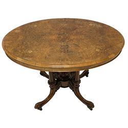 Victorian inlaid walnut centre table, the quarter-match veneer oval top with boxwood and ebony stringing and foliate inlay, raised on a cluster column base with fluted and lobe carved pilasters surrounding a central finial, the platford carved with scrolls and foliate decoration, terminating in splayed cabriole supports with brass and ceramic castors