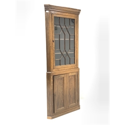 Early 19th century oak floor standing corner cupboard, projecting cornice over astragal glazed door enclosing three shelves, panelled cupboard door under enclosing another shelf, 