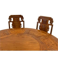 Chinese hardwood dining set - circular table with lazy Susan, panelled and carved with sub-aquatic scenes, on tri-form panelled base, together with set eight high back dining chairs carved with elephant masks and foliate motifs