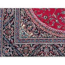 Persian design crimson ground rug, the field decorated with circular medallion surrounded by trailing branches and foliate motifs, the spandrels and border decorated with stylised plant motifs 