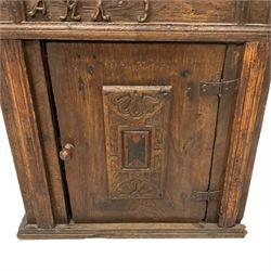 17th century oak bible box on cupboard, hinged sloped top with moulded edge, decorated with applied central panel carved with floral lunettes, frieze decorated with applied lettering, over the single cupboard door with matching panel, on moulded skirted base