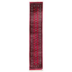Tekke Bokhara red ground runner, the field decorated with a single row of Gul motifs, panelled border each with stylised motif