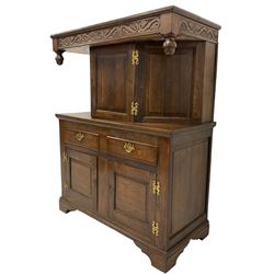 19th century oak court cupboard, the projecting top carved with foliate s-scrolls, canted cupboard with panelled door and sides, fitted with two drawers and two panelled cupboards with walnut banding, on bracket feet