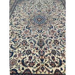 Persian ivory ground rug, central rosette medallion surrounded by stylised peony motifs and trailing leafy branches, the spandrels matching the medallion, repeating scrolling border with stylised plant motifs, within guard bands