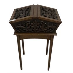 20th century carved oak workbox on stand, tapering rectangular form enclosed by two sloping hinged lids, decorated with curled acanthus leaf carved mounts, on square tapering supports 